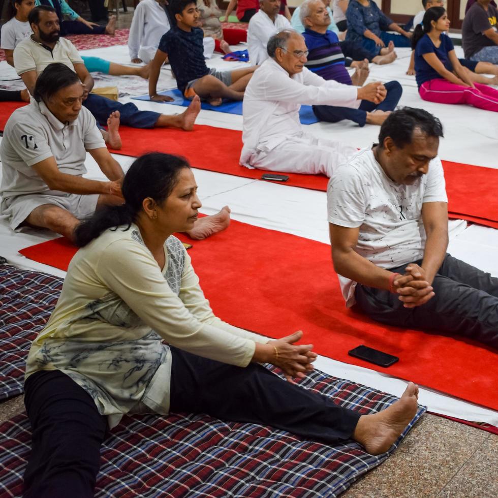 New Delhi, India, June 19 2022 -Group Yoga exercise session for people of different age groups in Balaji Temple, Vivek Vihar, International Yoga Day, Big group of adults attending yoga class in temple photo