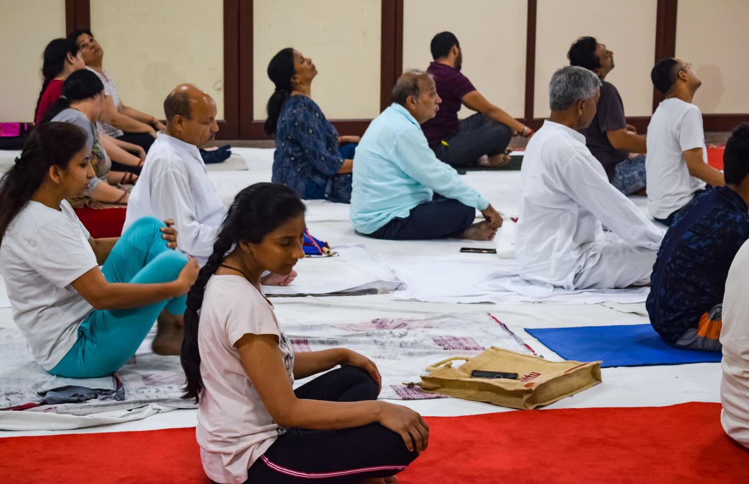 New Delhi, India, June 19 2022 -Group Yoga exercise session for people of different age groups in Balaji Temple, Vivek Vihar, International Yoga Day, Big group of adults attending yoga class in temple photo