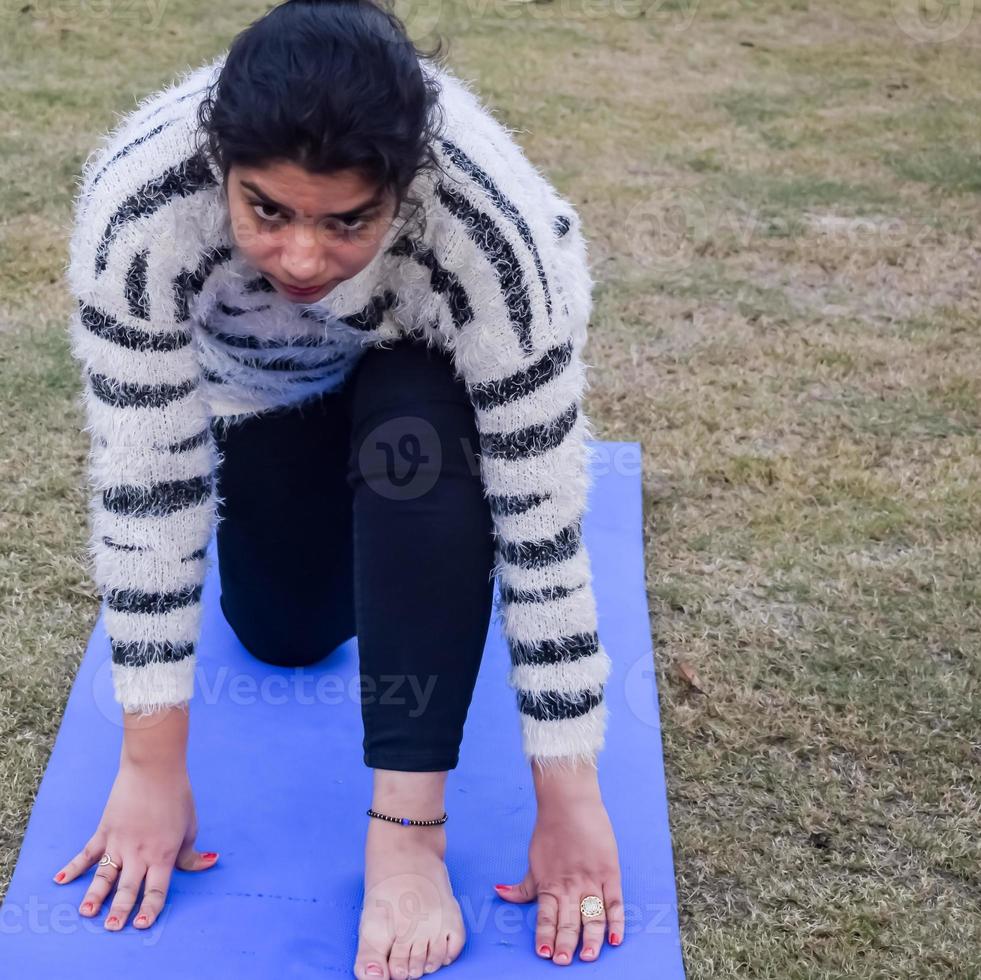 Young Indian woman practicing yoga outdoor in a park. Beautiful girl practice basic yoga pose. Calmness and relax, female happiness. Basic Yoga Exercise outdoor photo