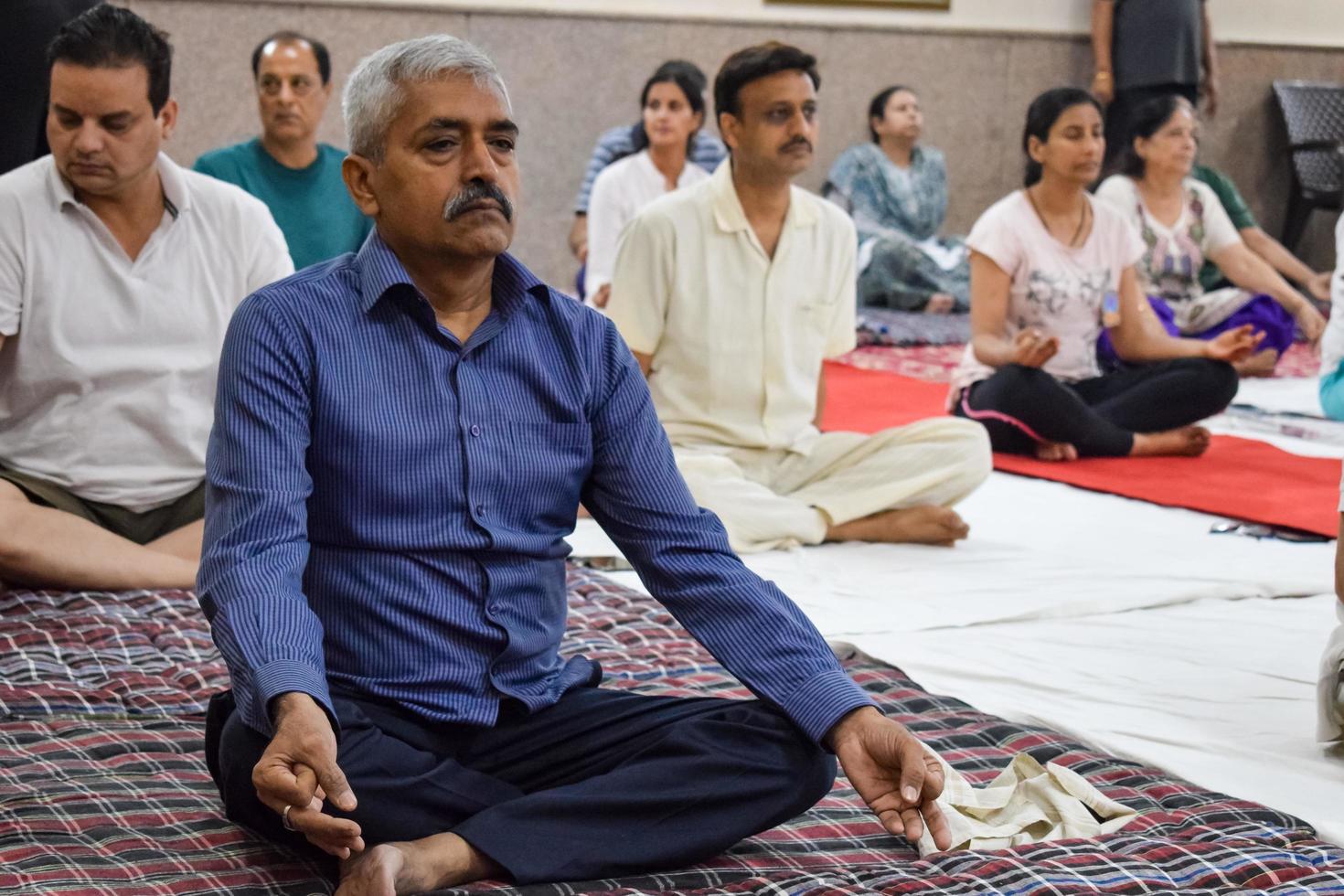 New Delhi, India, June 19 2022 -Group Yoga exercise session for people of different age groups in Balaji Temple, Vivek Vihar, International Yoga Day, Big group of adults attending yoga class in temple photo