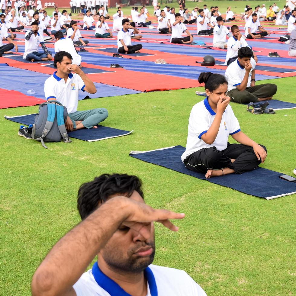 New Delhi, India, June 21 2022 - Group Yoga exercise session for people at Yamuna Sports Complex in Delhi on International Yoga Day, Big group of adults attending yoga class in cricket stadium photo