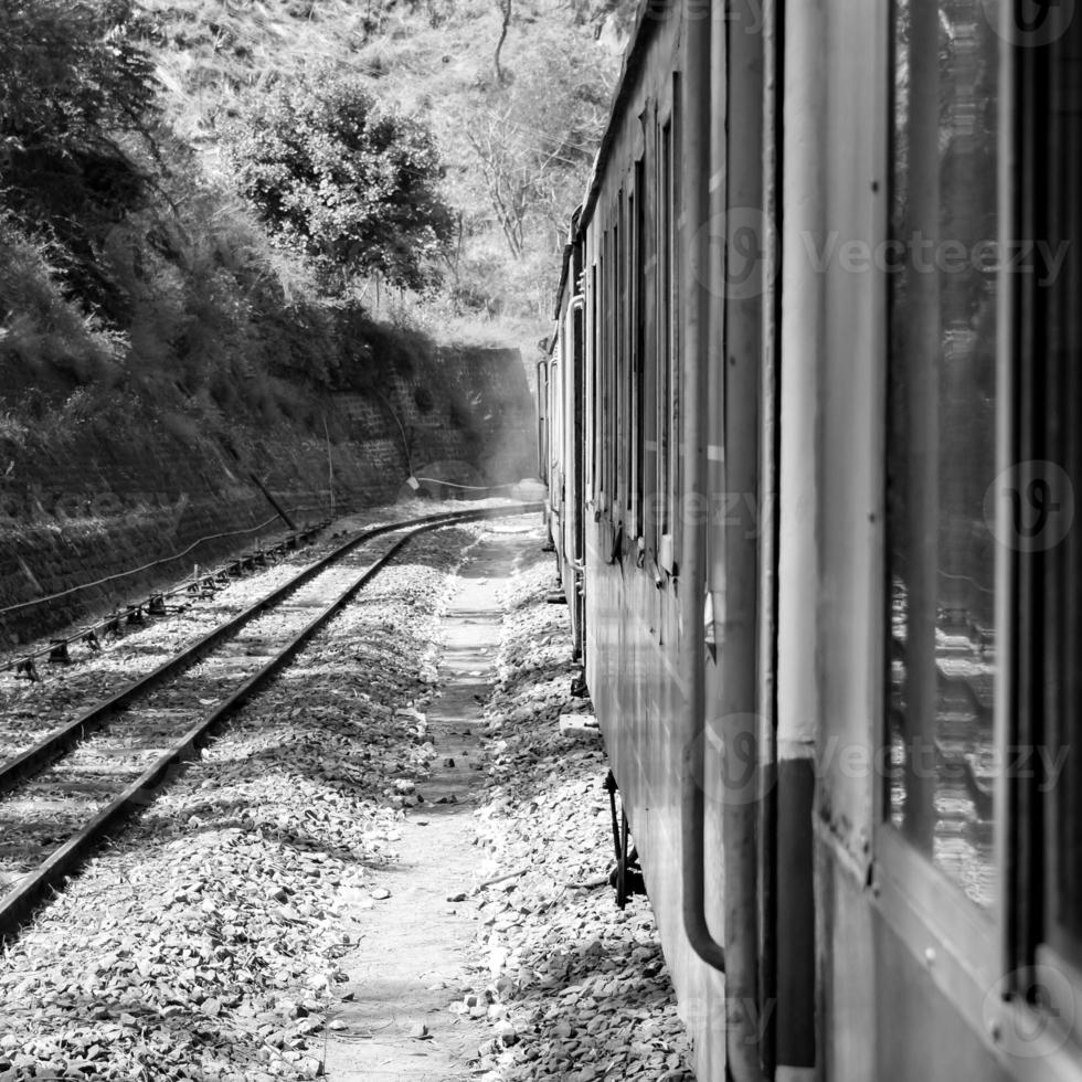 tren de juguete moviéndose en la ladera de la montaña, hermosa vista, montaña de un lado, valle de un lado moviéndose en ferrocarril a la colina, entre bosques naturales verdes.tren de juguete de kalka a shimla en india-blanco y negro foto