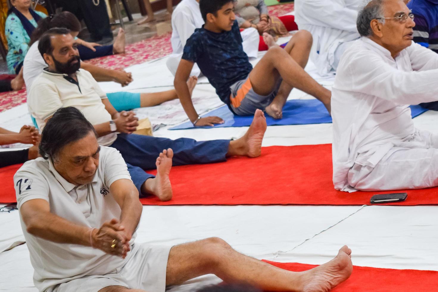 New Delhi, India, June 19 2022 -Group Yoga exercise session for people of different age groups in Balaji Temple, Vivek Vihar, International Yoga Day, Big group of adults attending yoga class in temple photo