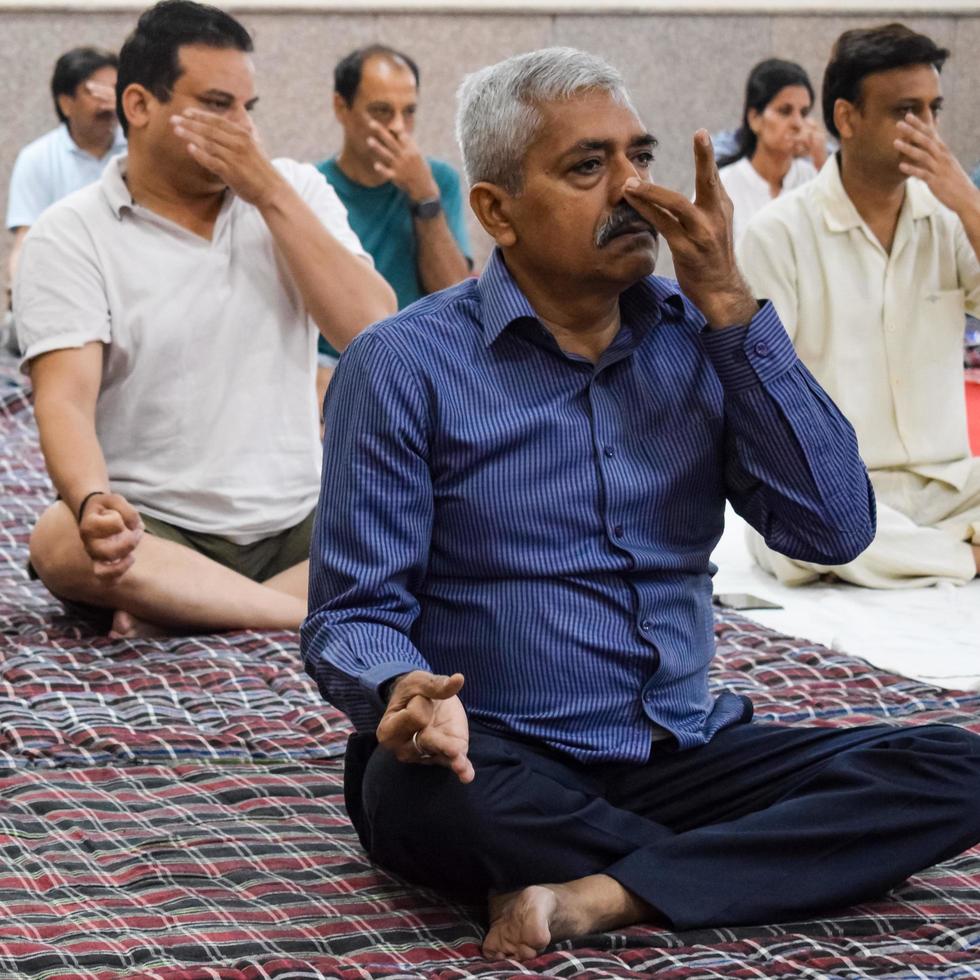 New Delhi, India, June 19 2022 -Group Yoga exercise session for people of different age groups in Balaji Temple, Vivek Vihar, International Yoga Day, Big group of adults attending yoga class in temple photo