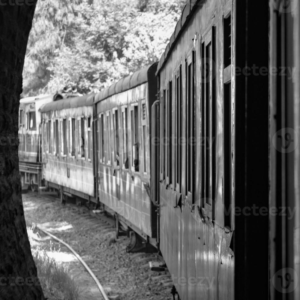 Toy Train moving on mountain slope, beautiful view, one side mountain, one side valley moving on railway to the hill, among green natural forest.Toy train from Kalka to Shimla in India-Black and White photo