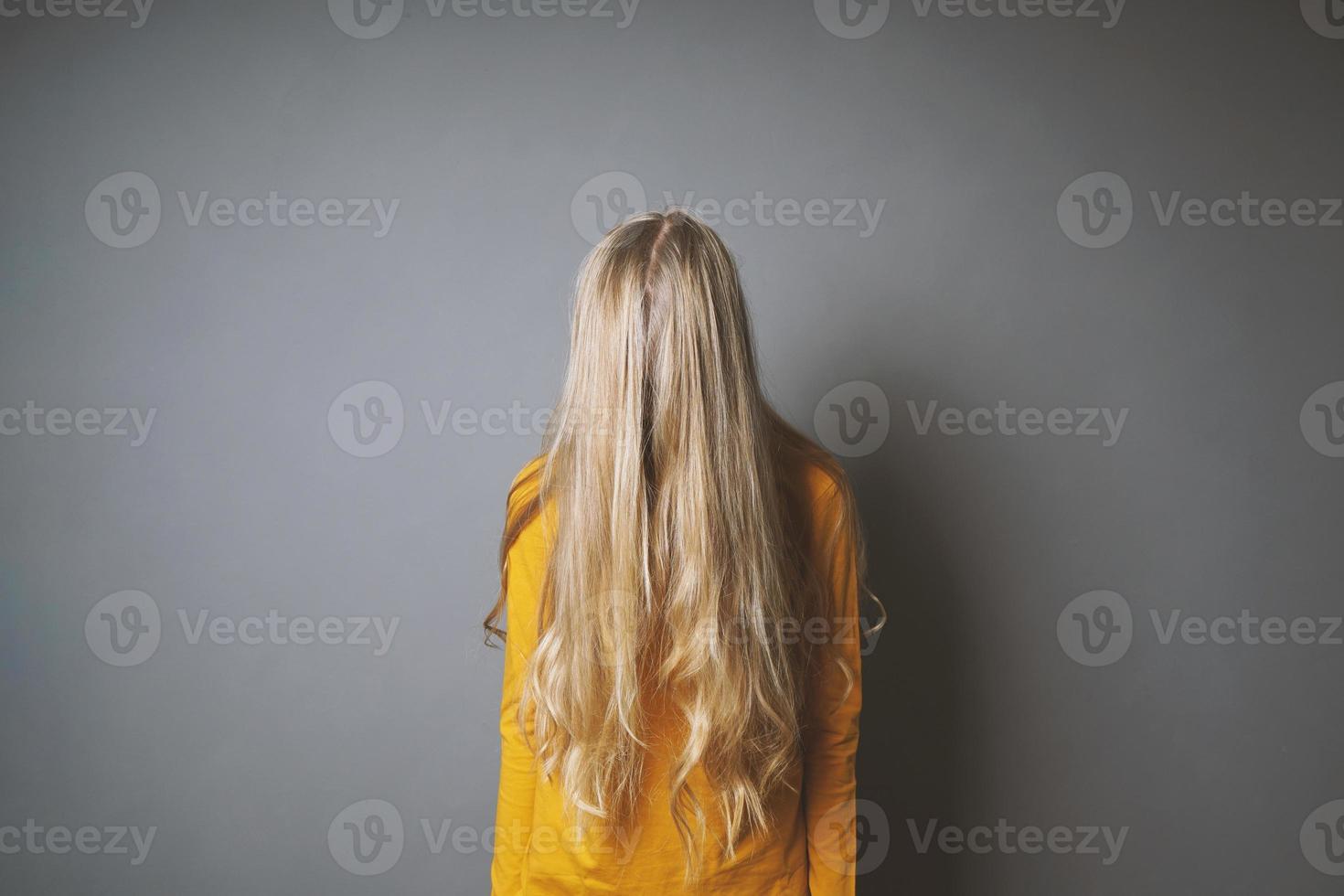 depressed young woman hiding her face behind long blond hair photo