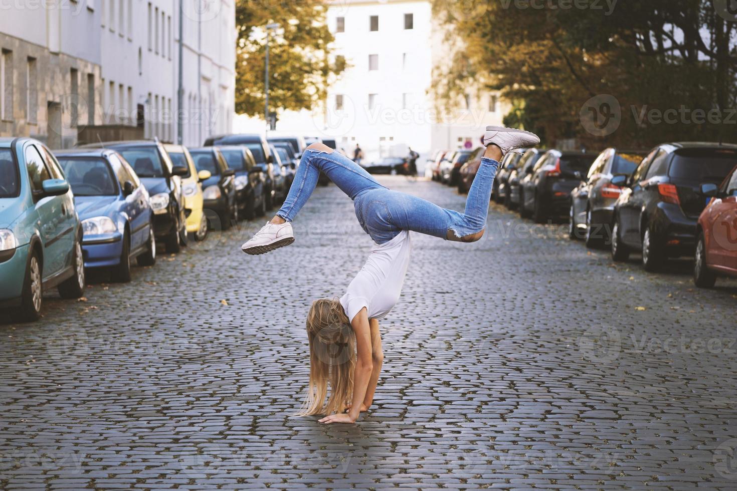young woman doing handstand on city street photo