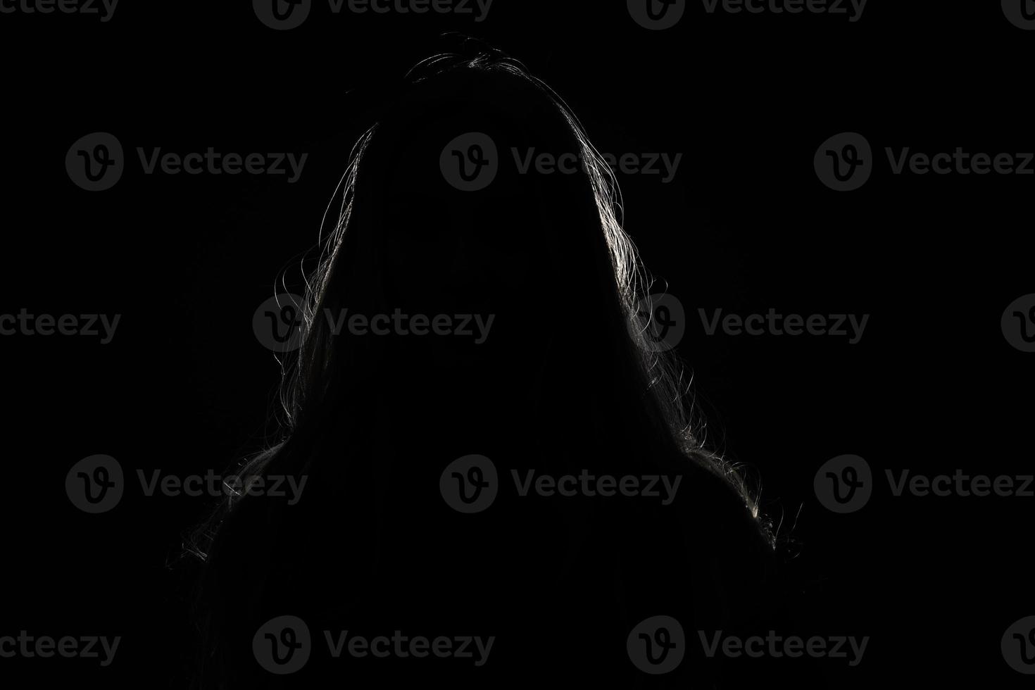 anonymous woman hiding face and identy in the dark shadow photo