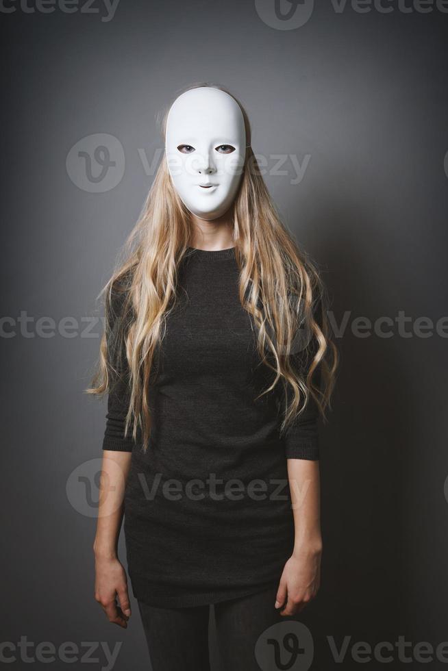 mysterious woman hiding face and identity behind white mask photo