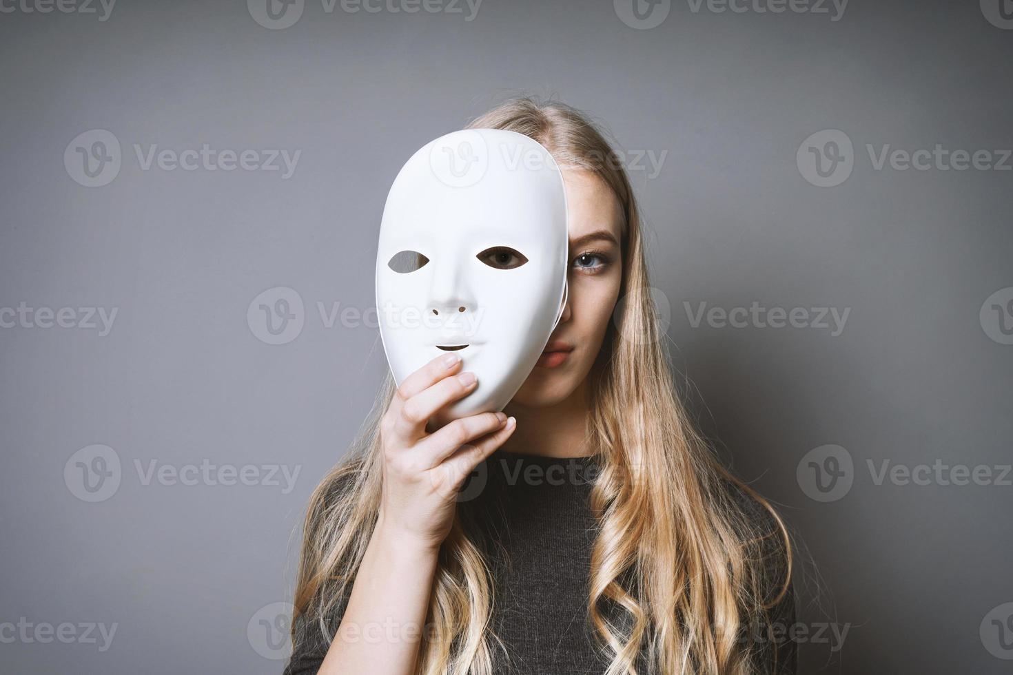 teen girl hiding face behind mask photo