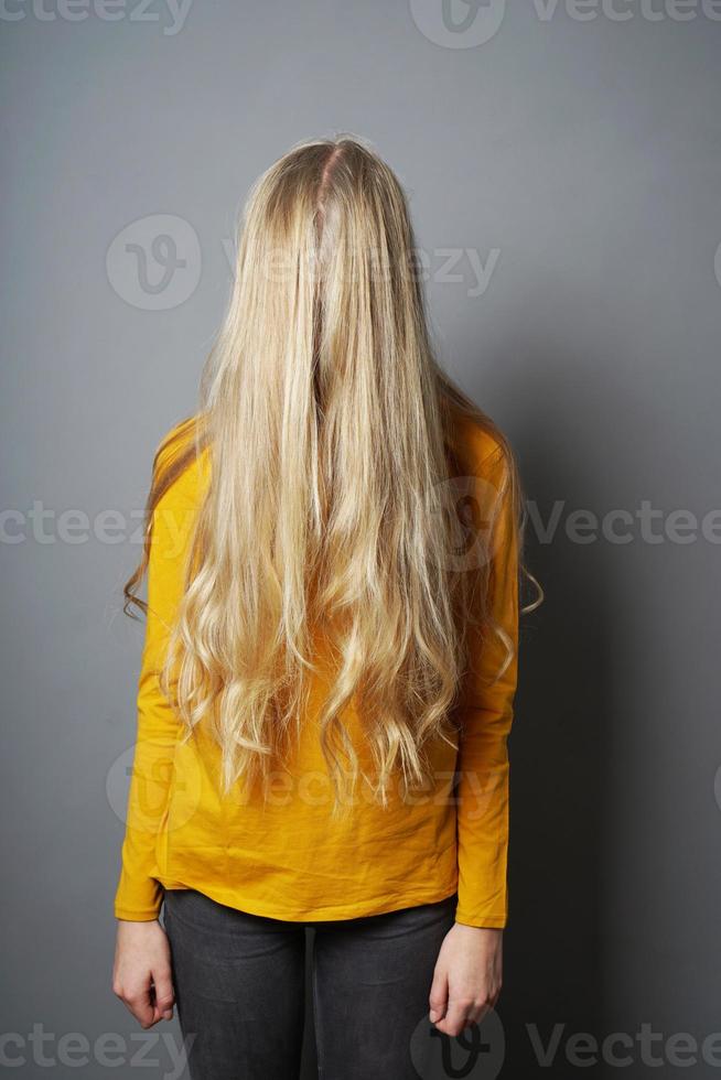 shy young woman with obscured face behind long blond hair photo