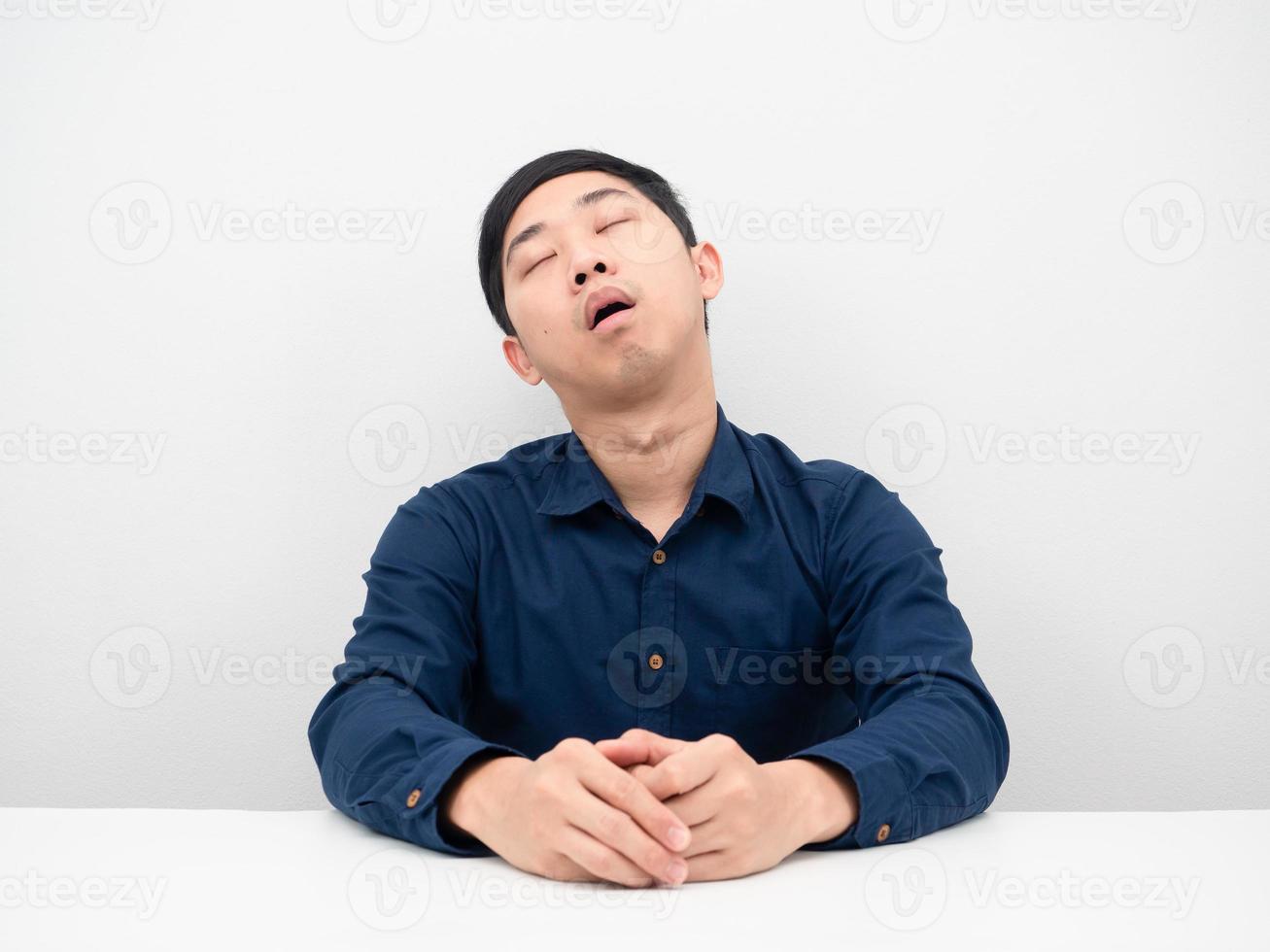 hombre asiático durmiendo profundamente en la mesa sintiéndose probado por trabajar con fondo blanco foto
