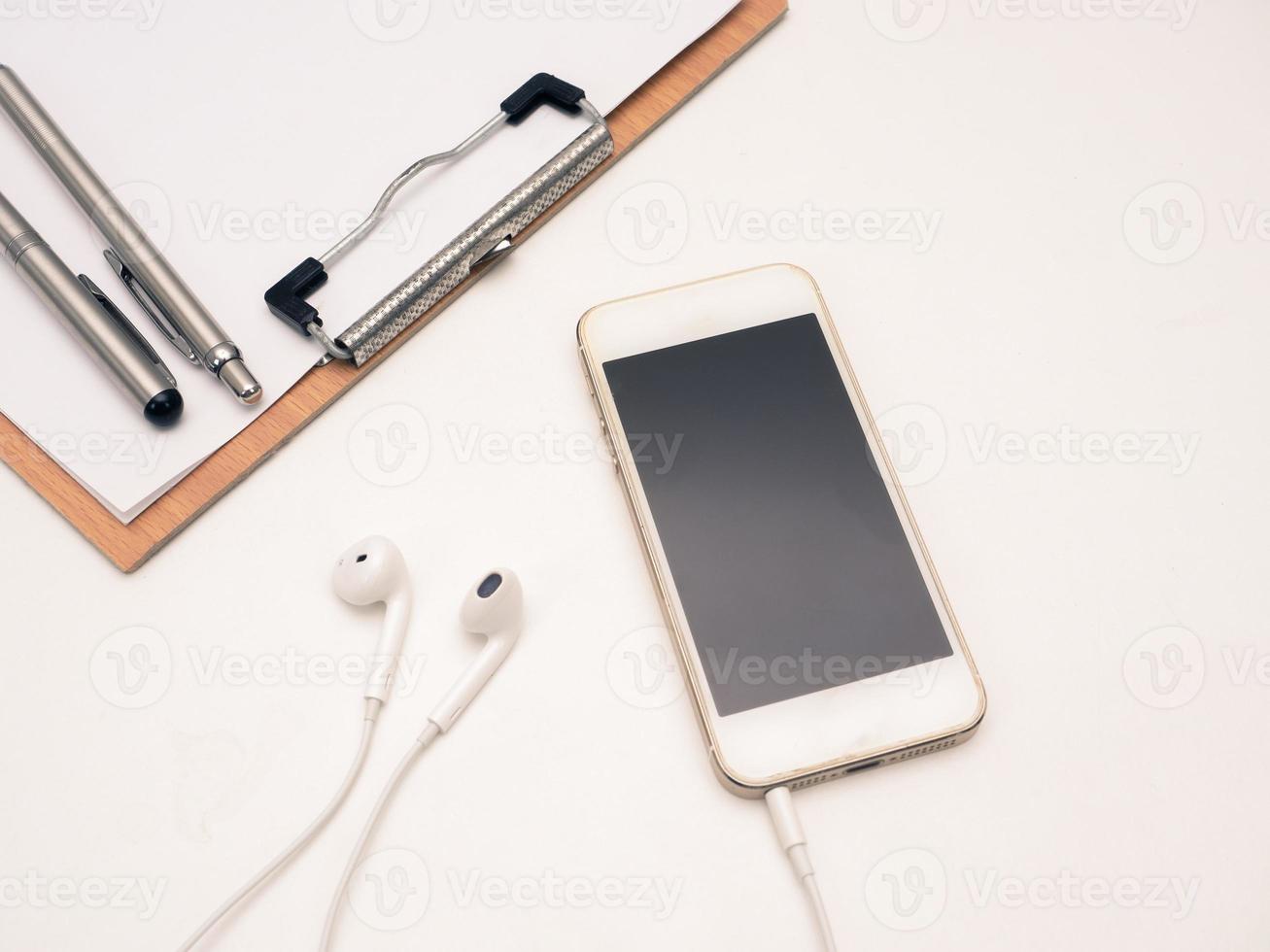 Close up mobile phone with ear phone and wood board document on table photo