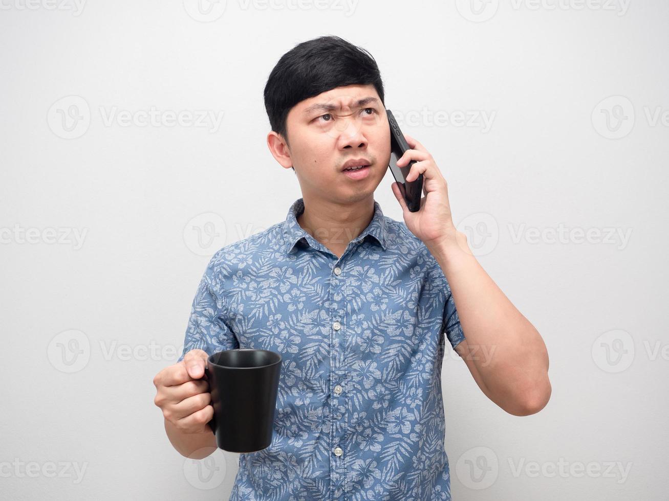 hombre camisa azul hablando con teléfono móvil y sosteniendo una taza de café emoción enojada foto