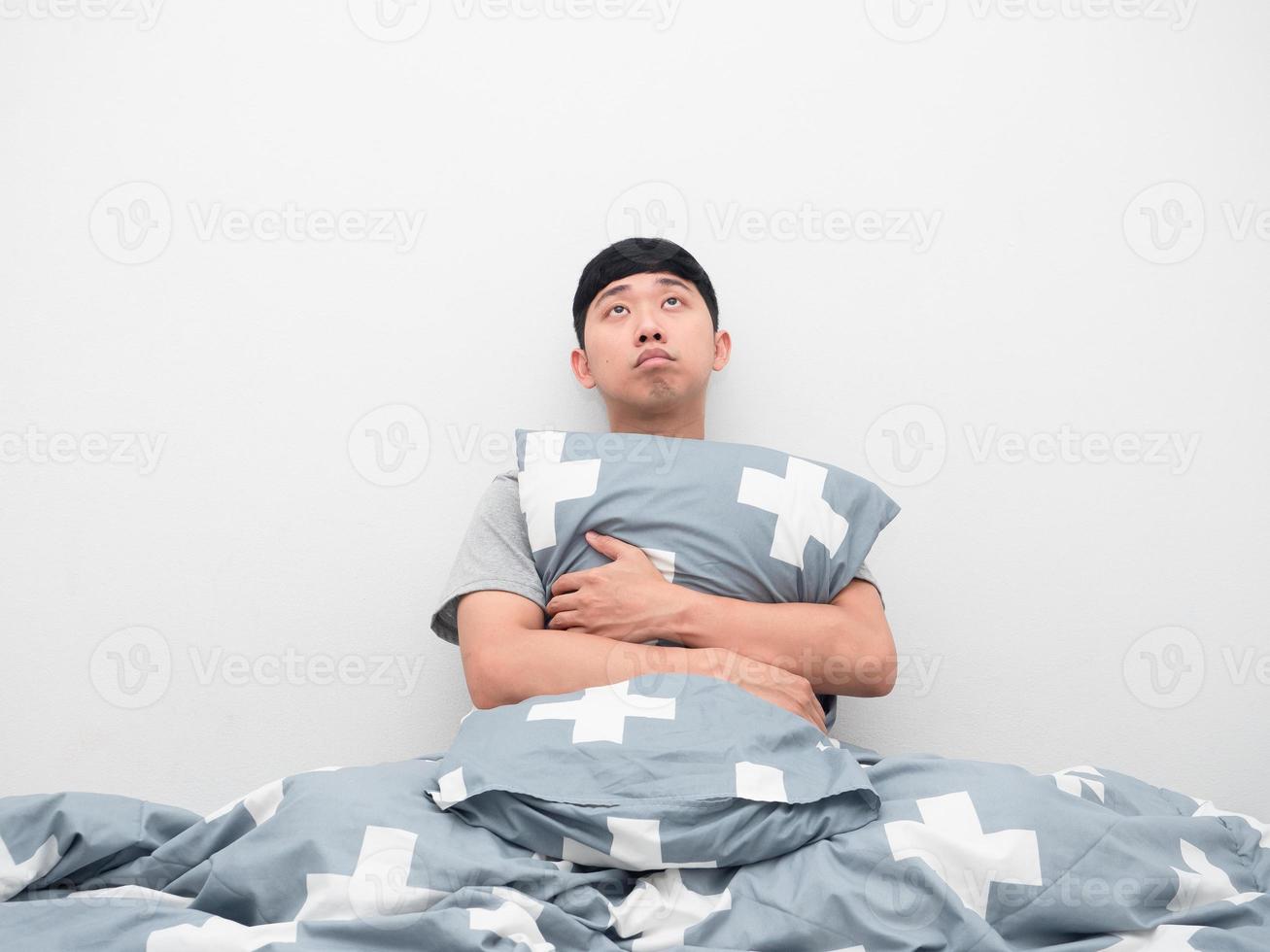 Man sit and hugging pillow feel sleepy and looking up photo