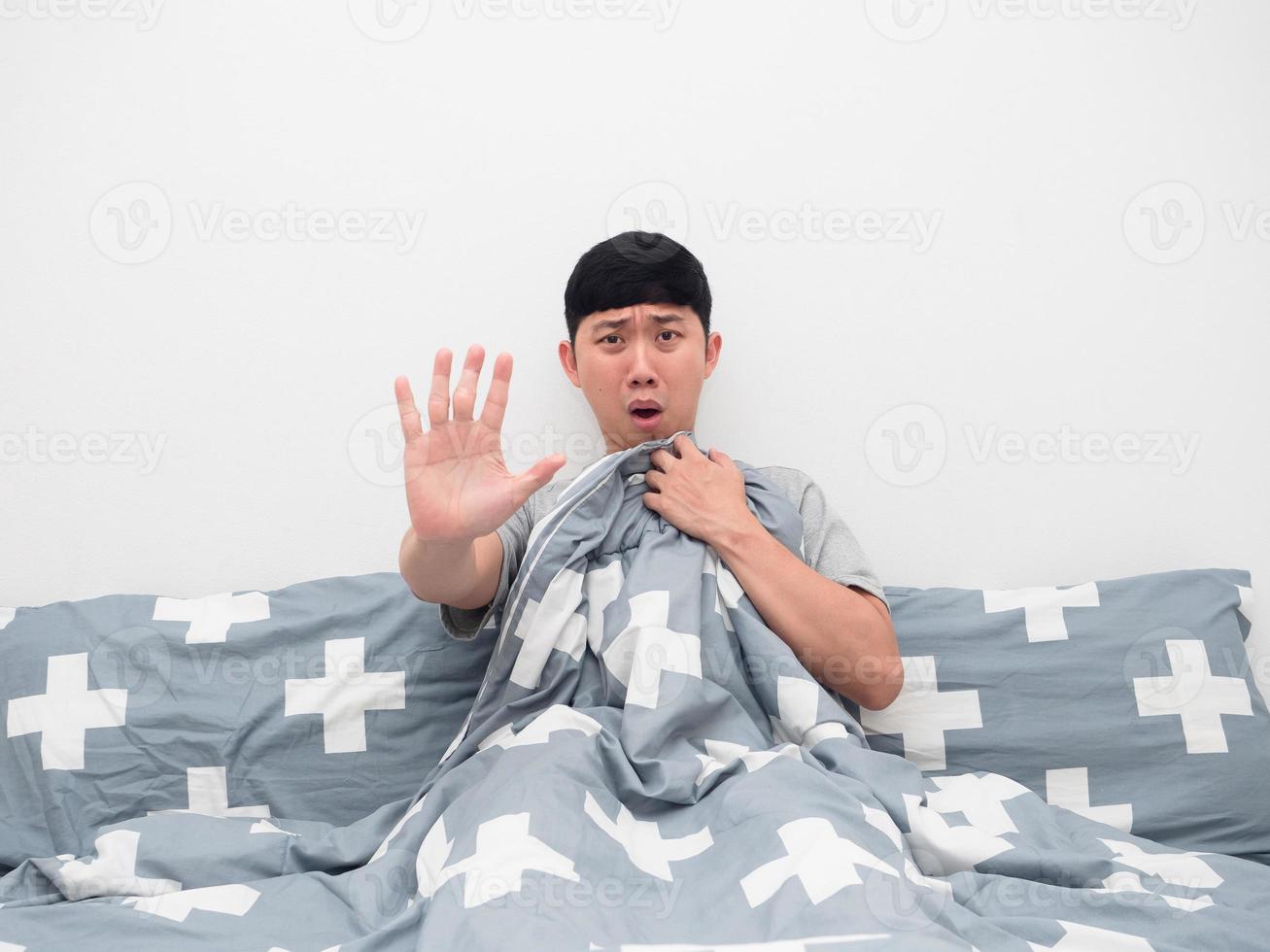 Man sitting on the bed cover blanket his body show hand stop fear emotion photo