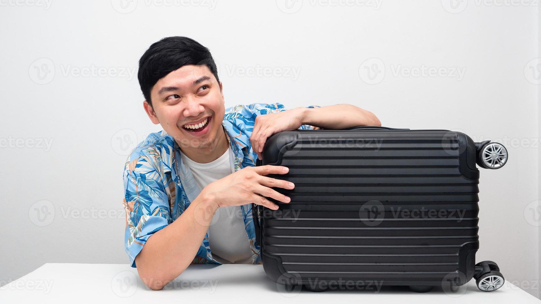 Cheerful man smiling hagging luggage looking above copy space photo