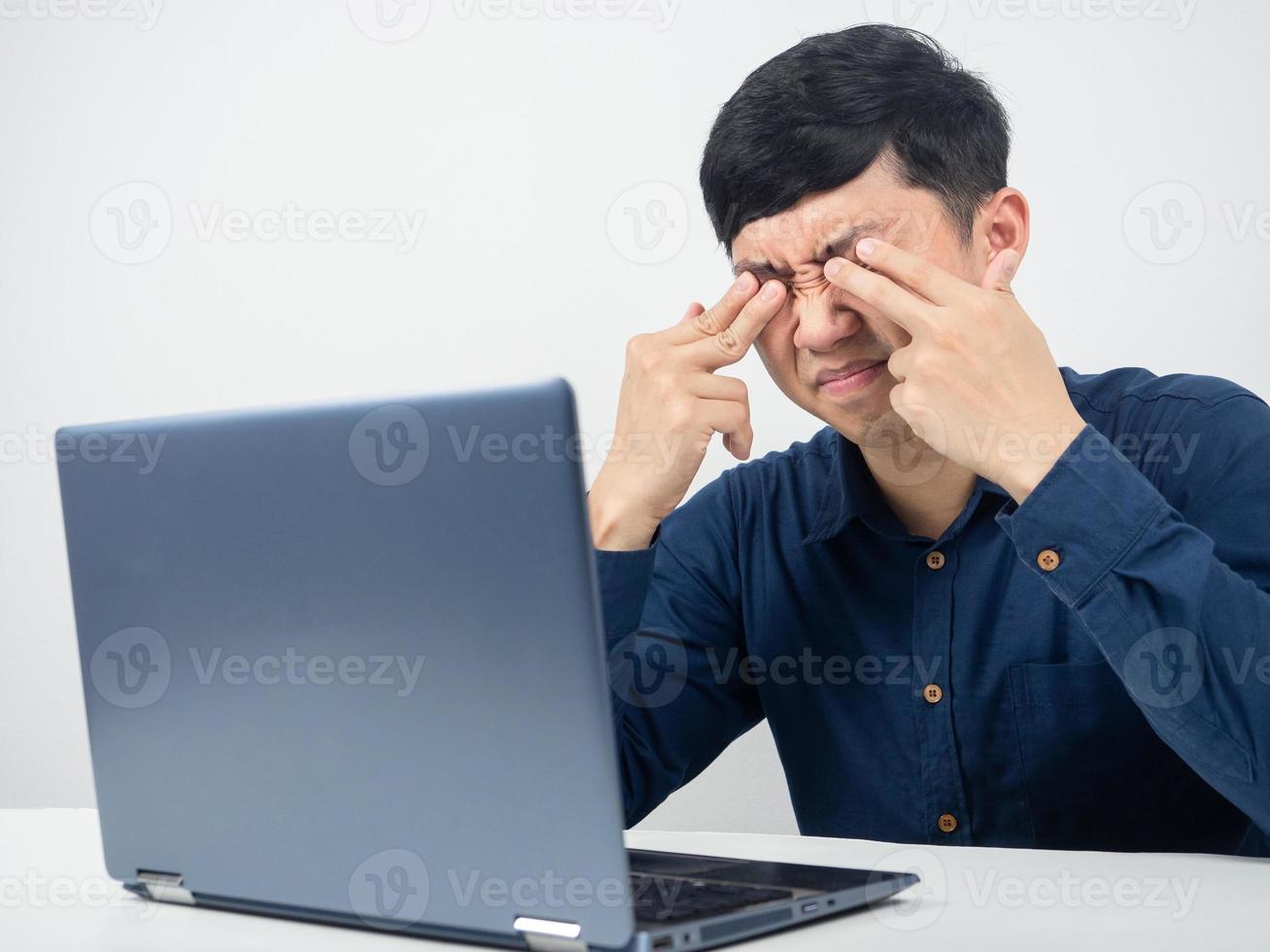 empleado masculino con computadora portátil trató de trabajar y siente fatiga visual, ojo aplastado foto