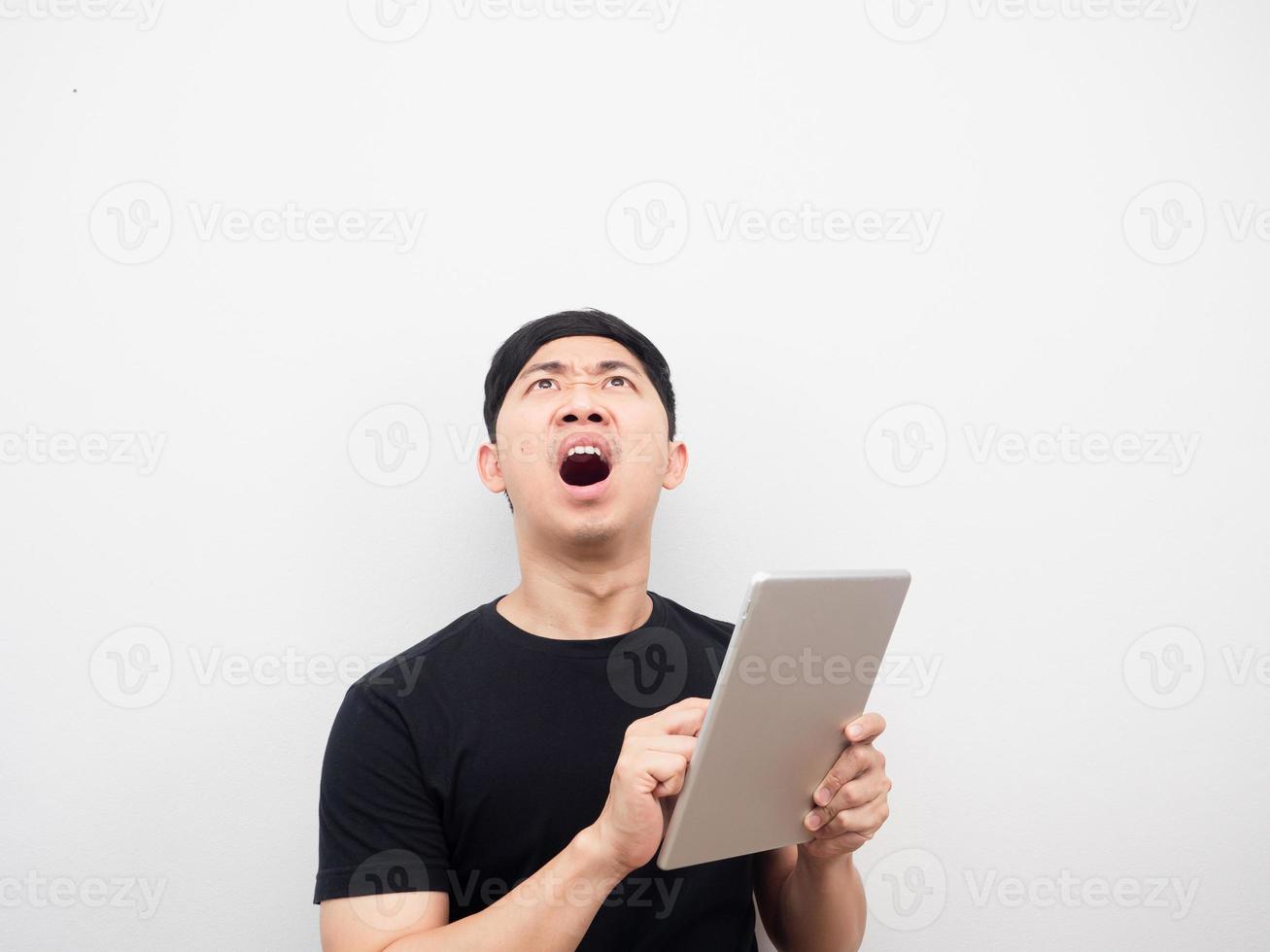 hombre usando tableta sintiéndose sorprendido y mirando por encima del espacio de copia foto