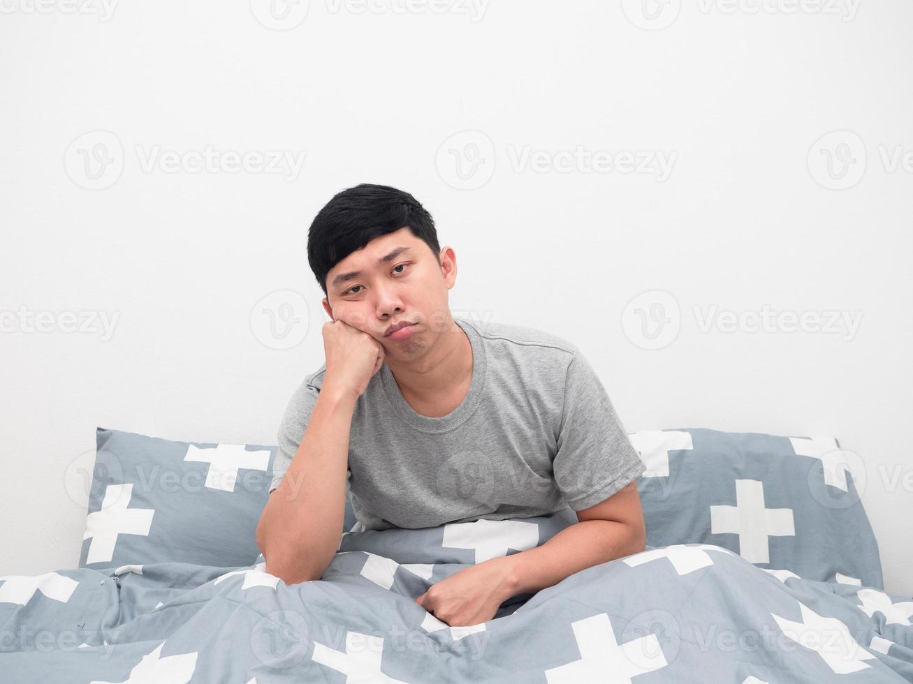 el hombre se sienta en el gesto de la cama aburrido mirando a la cámara foto