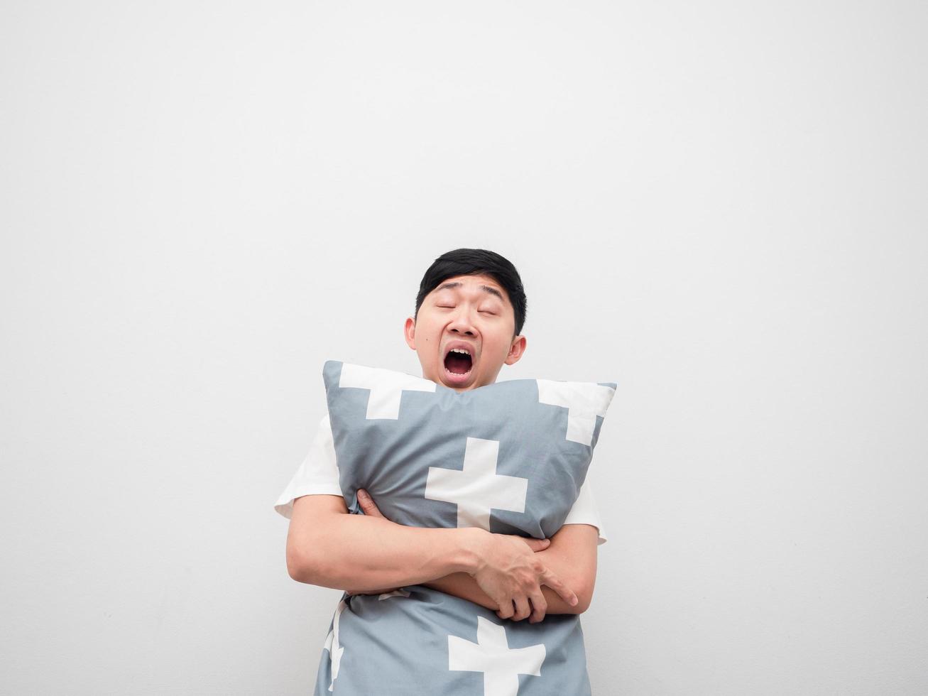 Asian sleepy man yawn and hug pillow on white background lazy concept photo