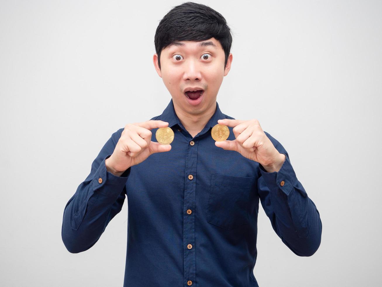 hombre asiático sosteniendo bitcoin dorado con cara asombrada sobre fondo blanco foto