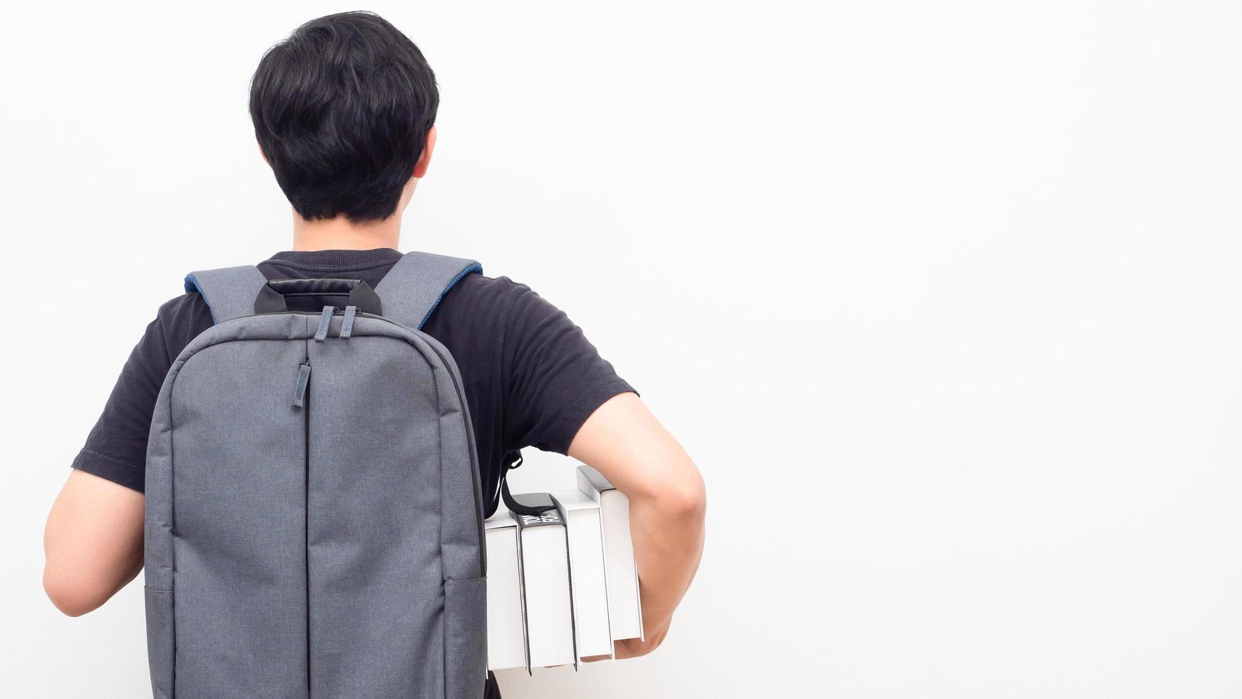 Man with school backpack and holding books stand turn back copy space white background back to school concept photo