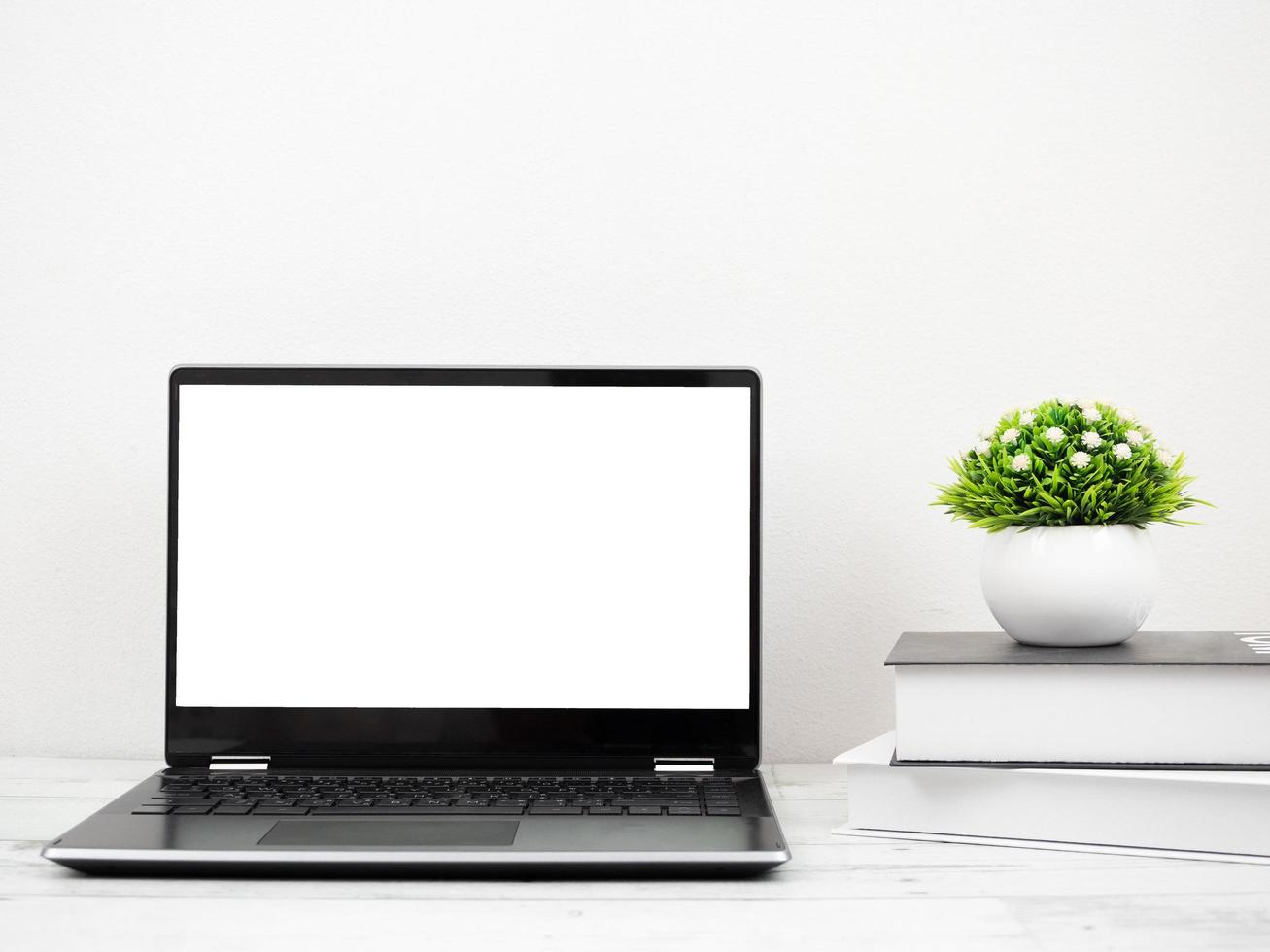 Laptop on the desk with book and vase workspace at home photo