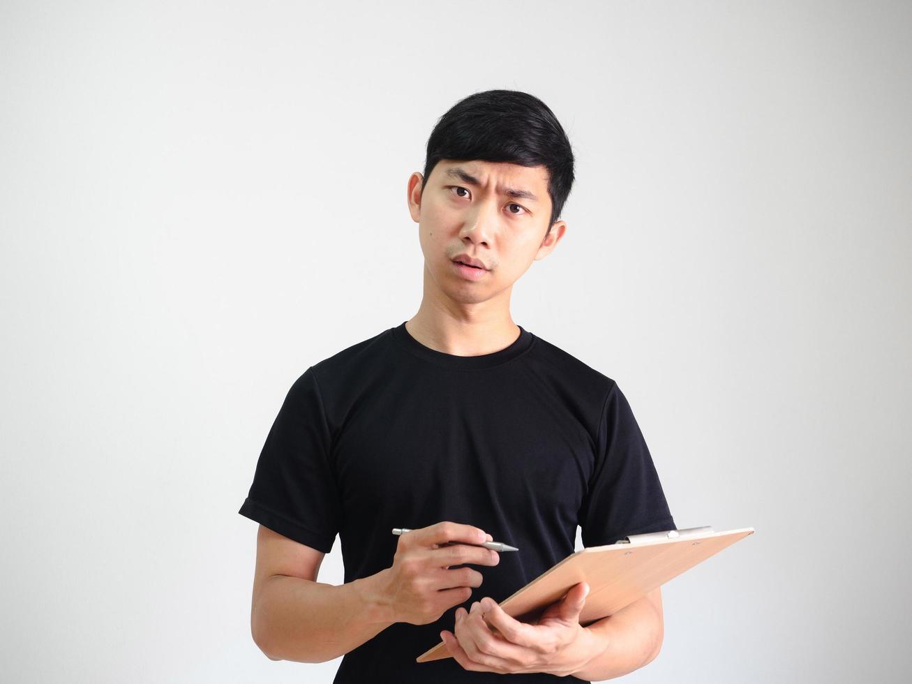 joven asiático sosteniendo portapapeles de madera y bolígrafo plateado en la mano cara seria mira la cámara en blanco aislado, concepto de trabajo foto