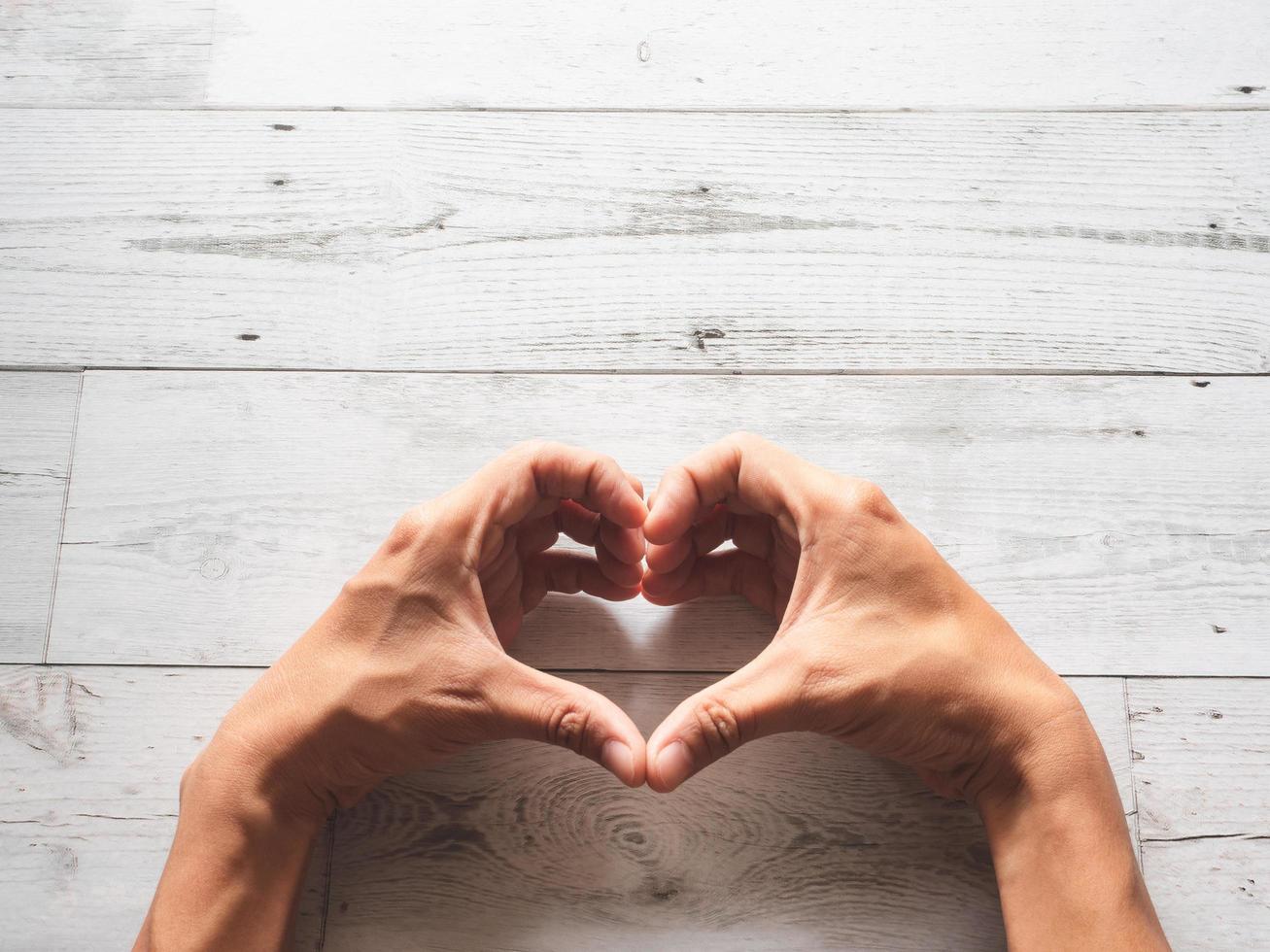 Hand heart on wood background with sunlight and nature shadow top view,Love and healthy concept photo