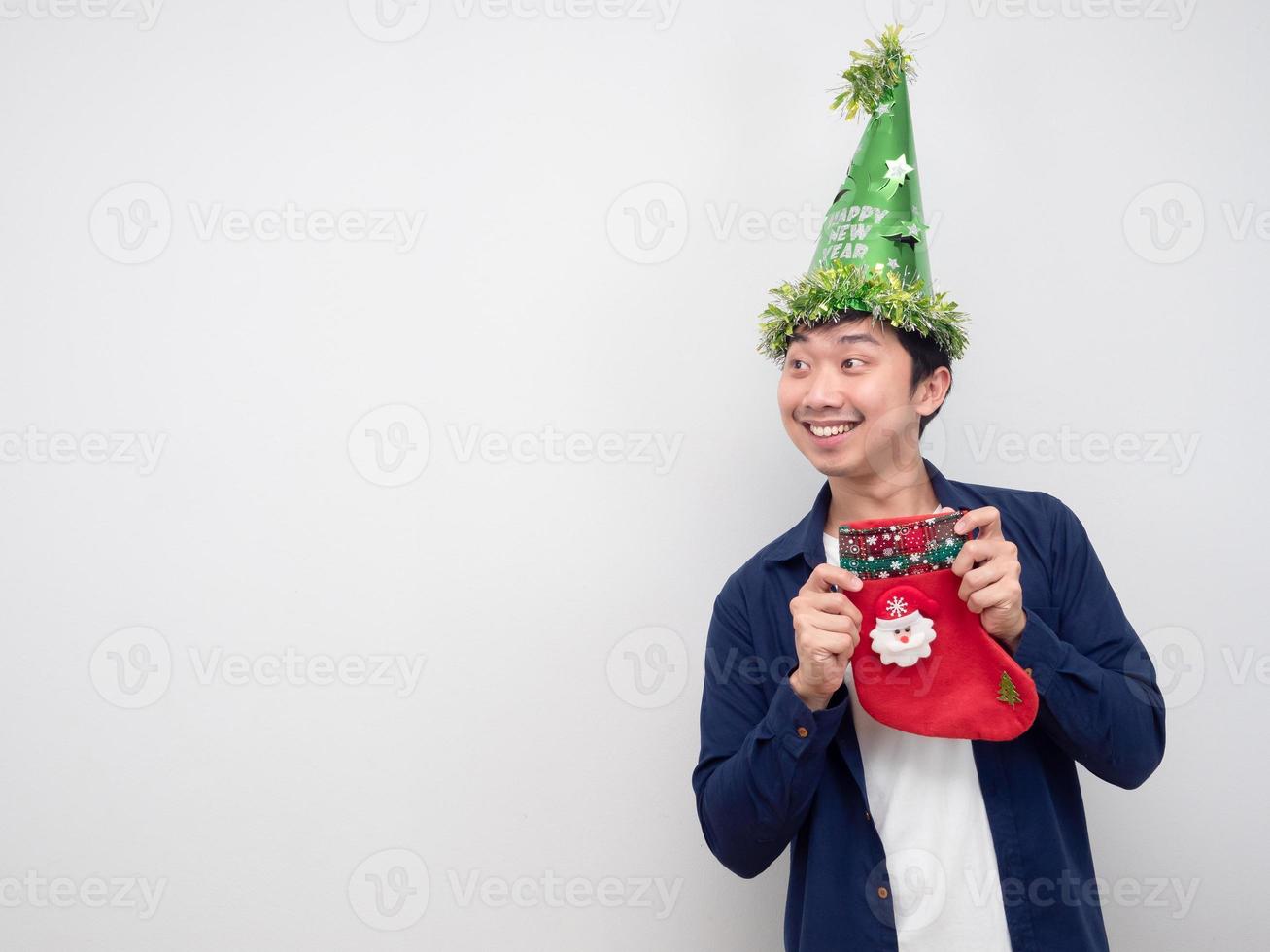 Asian man holding christmas stocking and looking at copy space white background photo