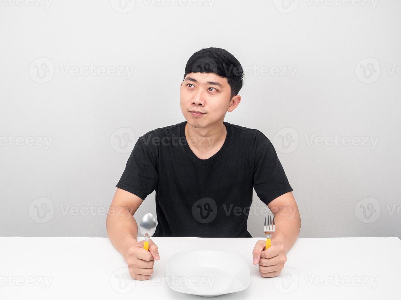 Man holding cutlery at the table looking at copy space thinking about dinner photo