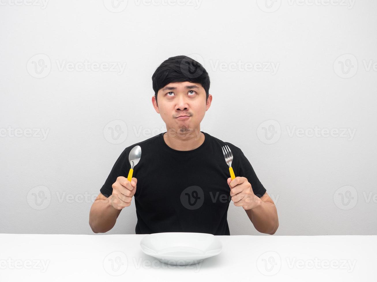 Man holding cutlery feeling hungry and looking up at copy space photo