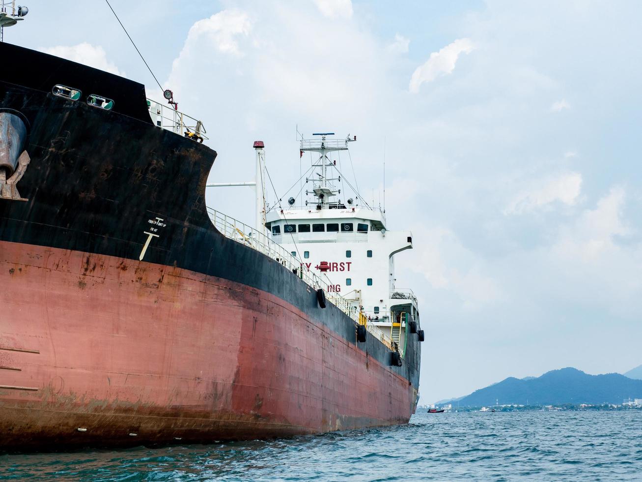 Big logistic ship unloading in the ocean with view mountain on island background and cloudy on sky,Shipping boat economy transportation concept on the sea photo