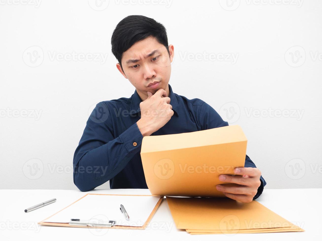 Man sitting at his workplace and thinking about document envolope in his hand in the table photo