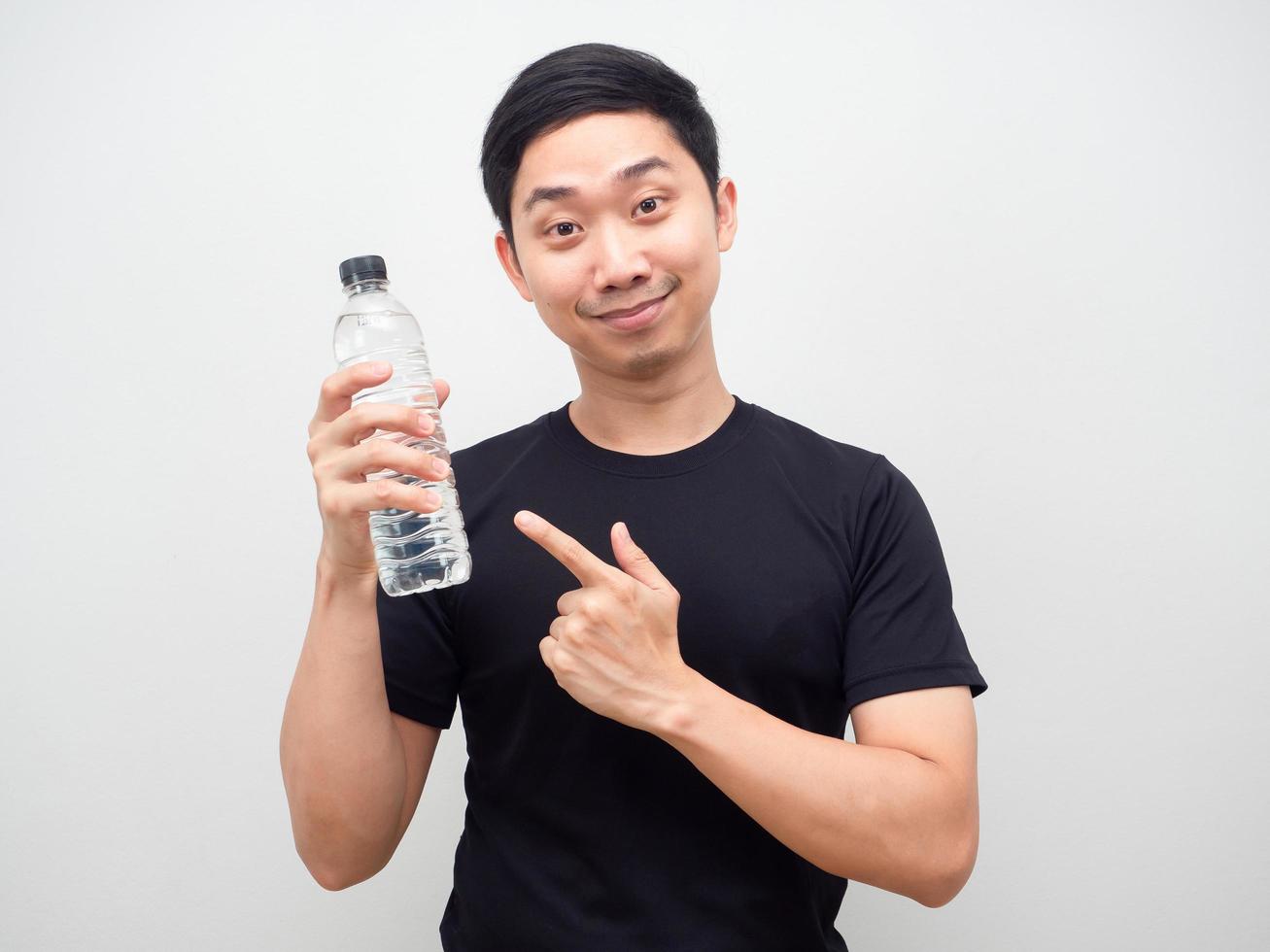 el hombre señala con el dedo la botella de agua en la mano con cara feliz de fondo blanco foto