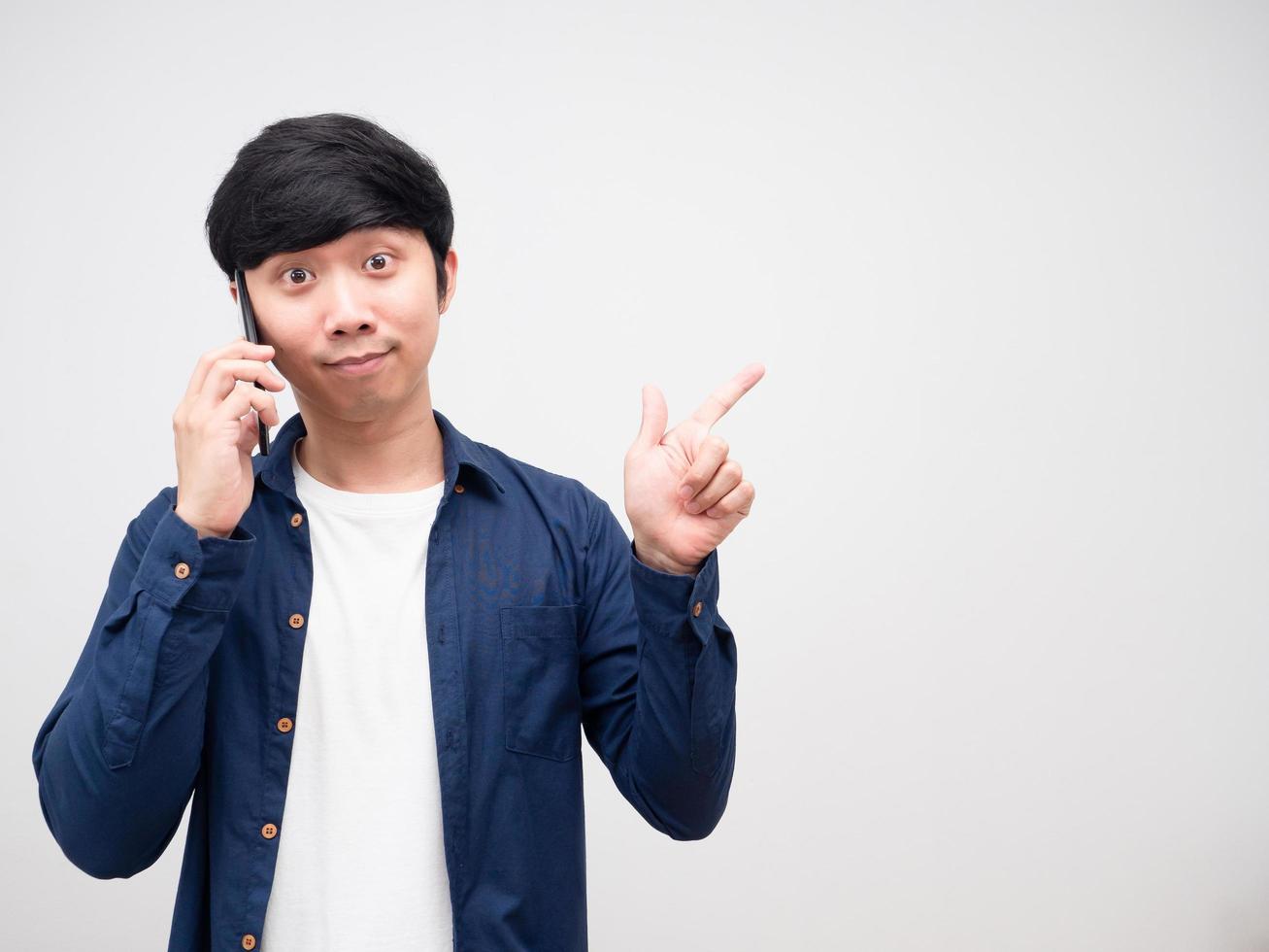 hombre guapo hablando con teléfono móvil y señalando con el dedo el fondo blanco del espacio de copia foto