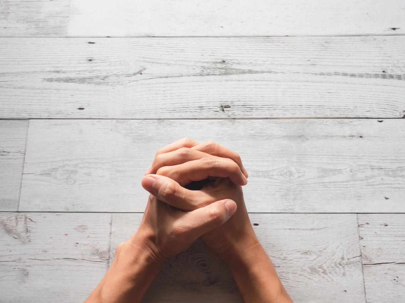 Closeup praying hands fist and sunlight nature shadow on wood table top view photo