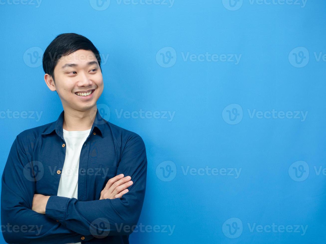 Asian man smile and cross arm looking at copy space blue background photo