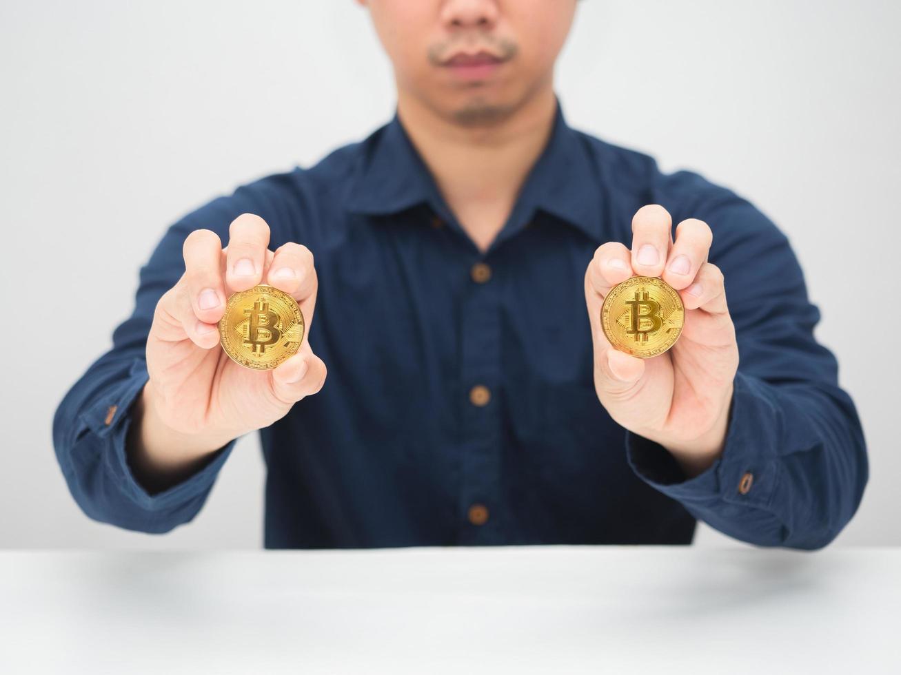 Man sitting at the desk and showing goldden bitcoin in his hand photo