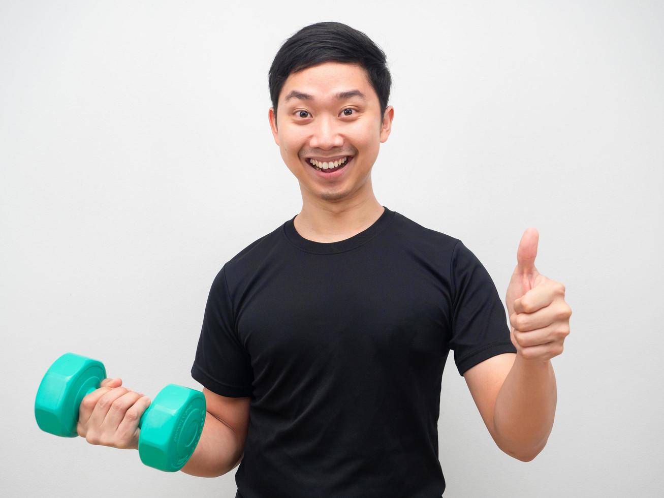 hombre sujetando drumbbell con sonrisa feliz pulgar arriba motivación concepto de entrenamiento foto