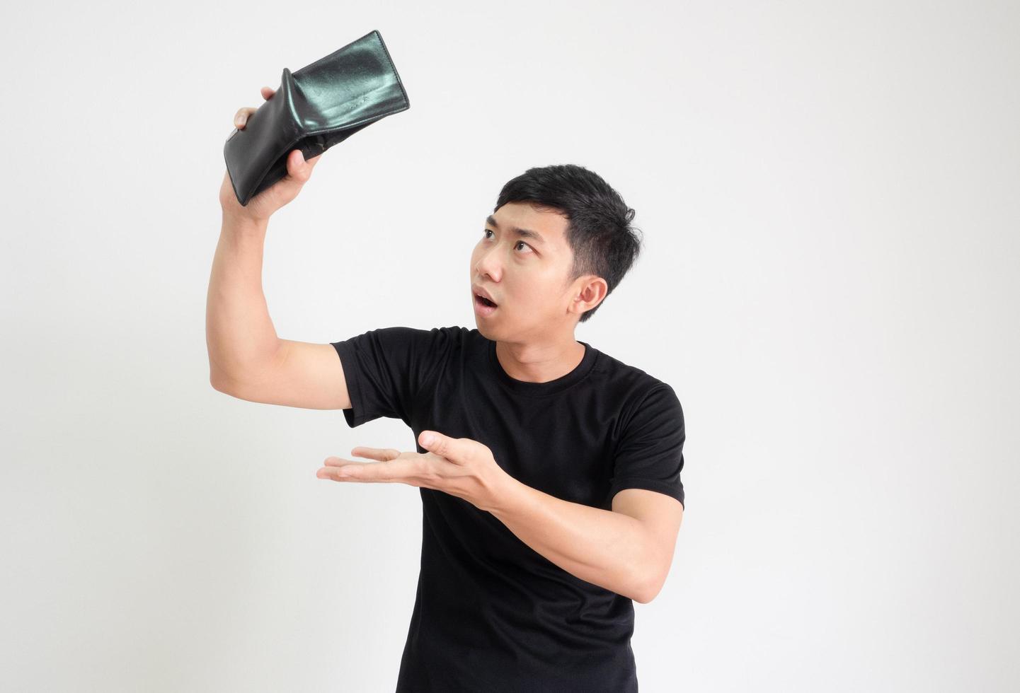 Young man black shirt holding and shake wallet in hand for find the money with shock face unhappy on white isolated,Poor man concept photo