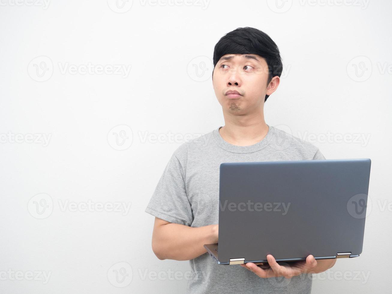 Asian man using laptop and feeling bored looking at copy space photo