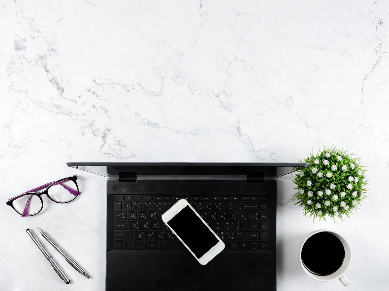 Workspace top view,Laptop mobile phone coffee cup and glasses on table copy space photo