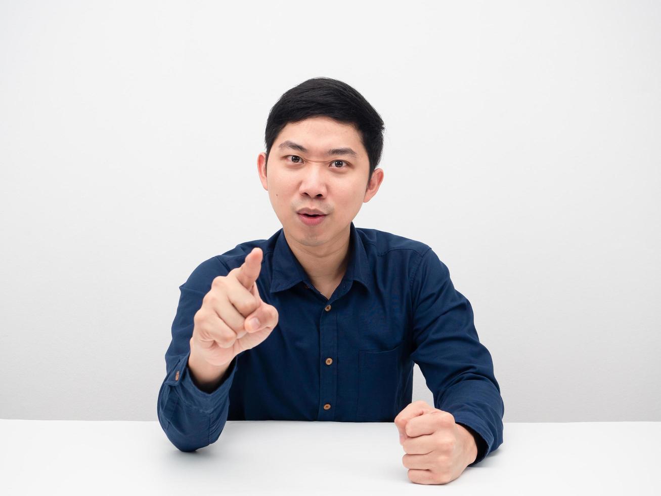 Asian man sitting at table feeling confident and point finger at you photo