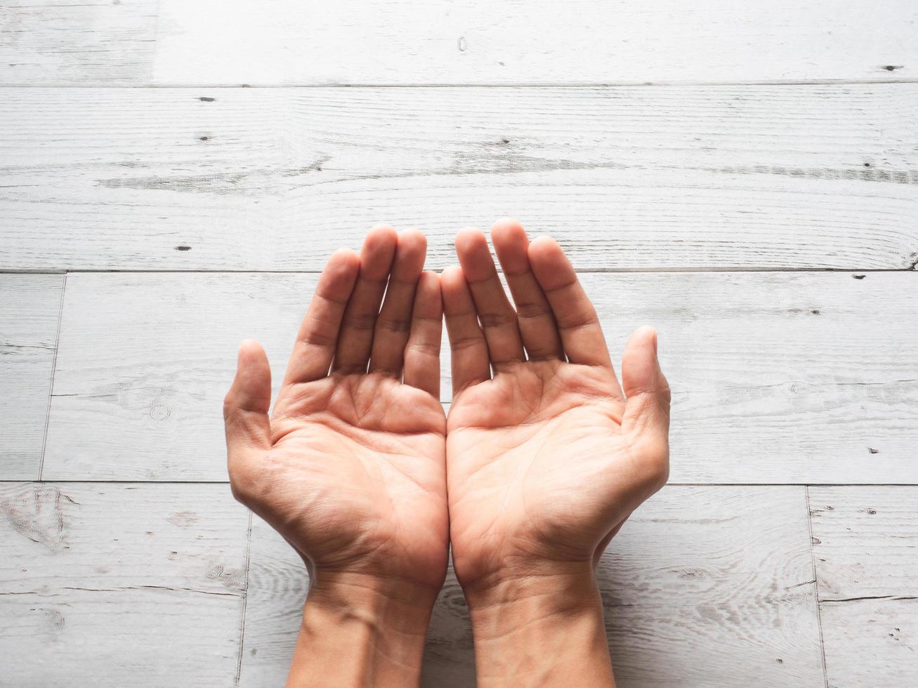 Closeup praying hands and sunlight nature shadow on wood table top view photo