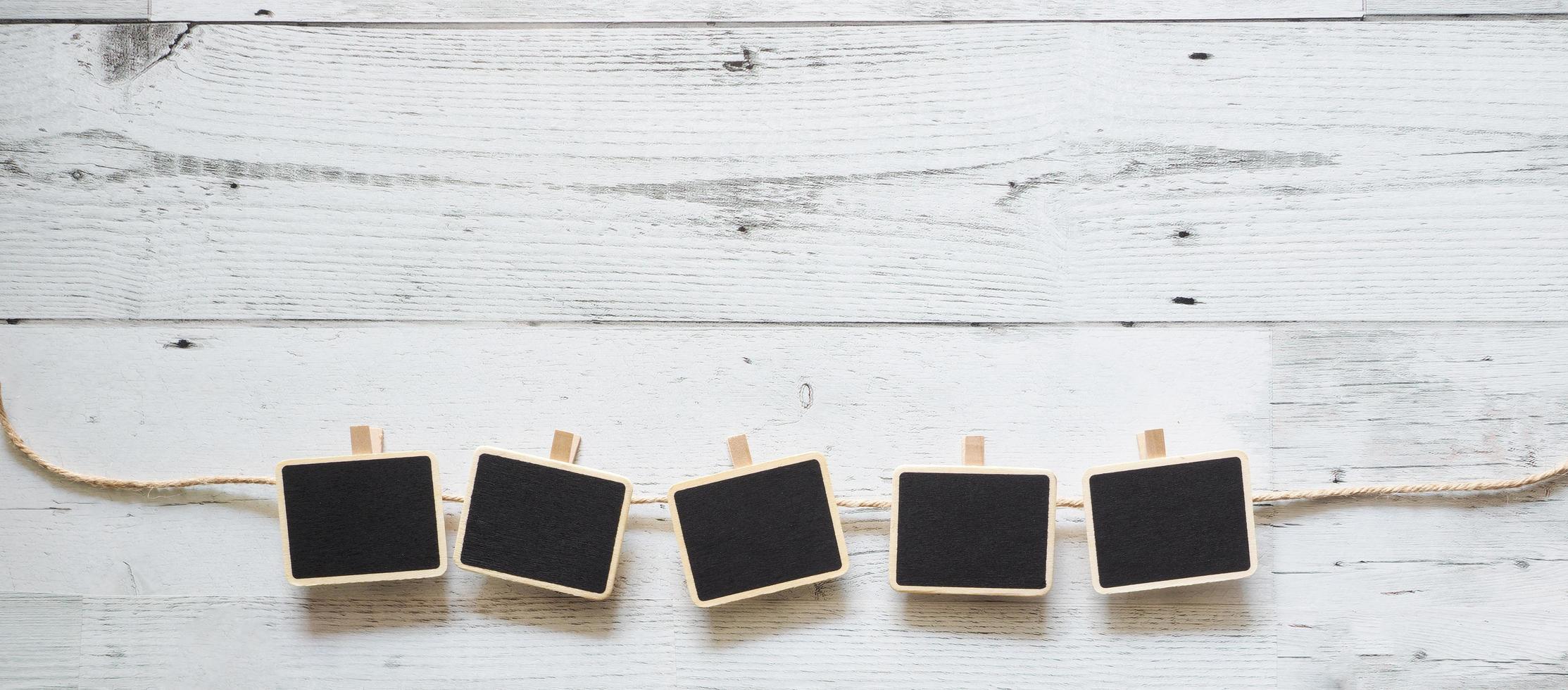 Five small clip chalkboard with rope array line on white wood table nature shadow below space,Idea signboard concept photo