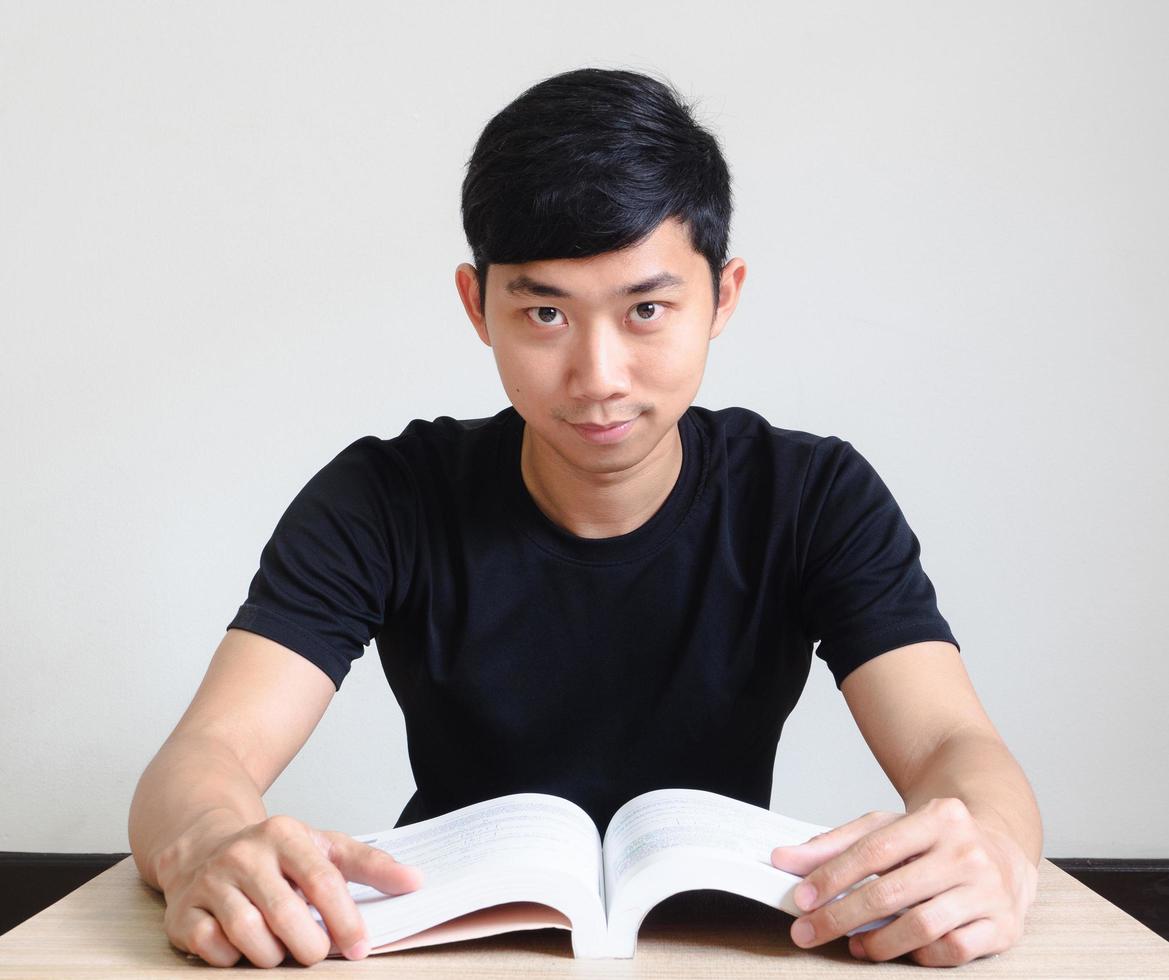 Young man sit at the desk with book and happy smile look at camera on white isolated,Education concept photo