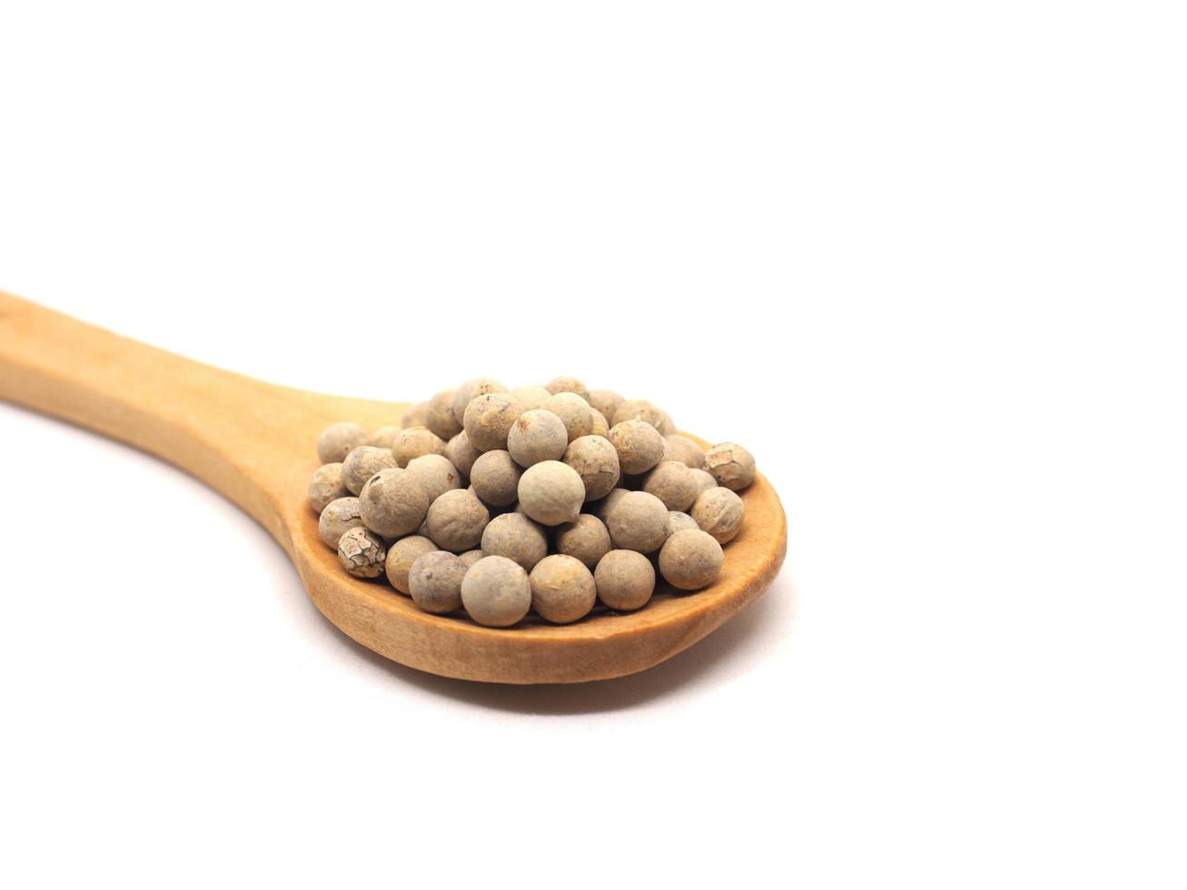 Closeup white peppers in wood spoon on white isolated natural shadow copy space ingredients kitchen concept photo