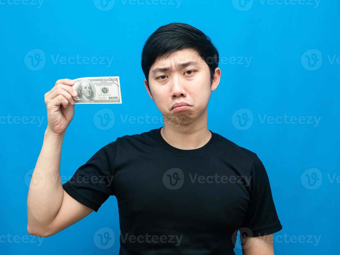 pobre hombre muestra dinero en su mano y siente tristeza emoción fondo azul foto